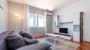 A modern living room with a grey sofa, a white coffee table, and a flat-screen TV on a white cabinet. - Beautiful home in Sukosan (Sukosan)