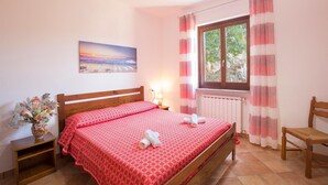 A bedroom with a bed, a nightstand, a chair, a window with curtains, a radiator, and a painting on the wall. - 3 bedroom nice apartment in Joppolo VV (Joppolo VV)