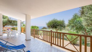 A covered outdoor area with a wooden railing, white chairs, and a table with a yellow pot. - 3 bedroom nice apartment in Joppolo VV (Joppolo VV)
