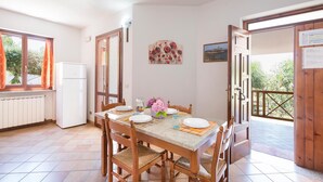 A dining area with a table set for four, a refrigerator, and a view of the outdoors. - 3 bedroom nice apartment in Joppolo VV (Joppolo VV)