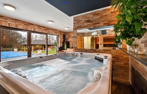Relax in a serene spa room with a hot tub, garden view, and starry night sky projection.