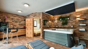 A modern bathroom with a large bathtub, a seating area with lounge chairs, and a starry sky projection on the wall.