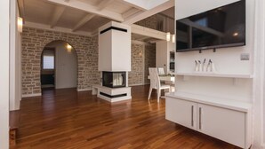 Een moderne woonkamer met een open haard, houten vloeren en een wandgemonteerde televisie.