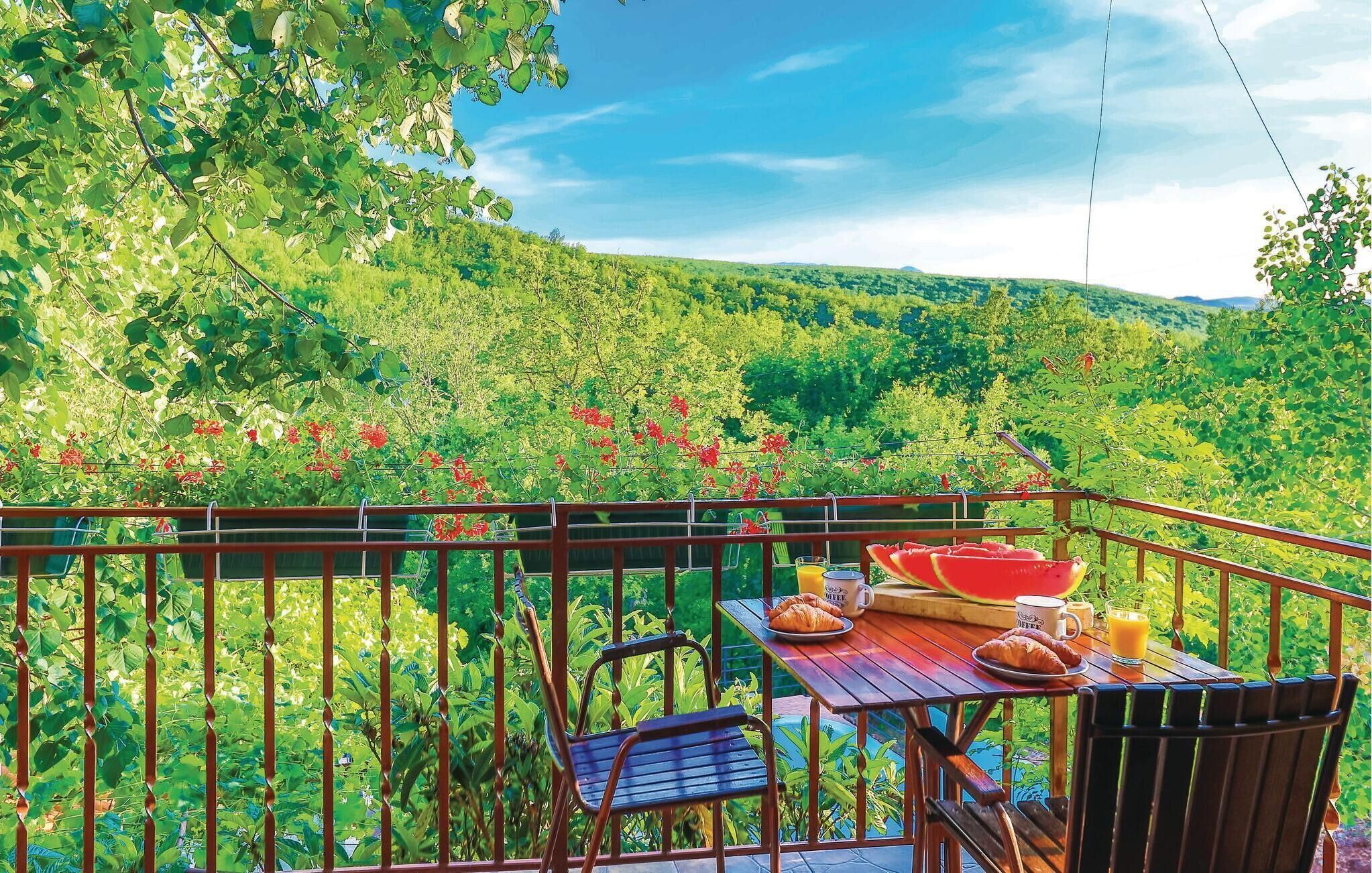 A balcony with a table set for breakfast, overlooking a lush green landscape.