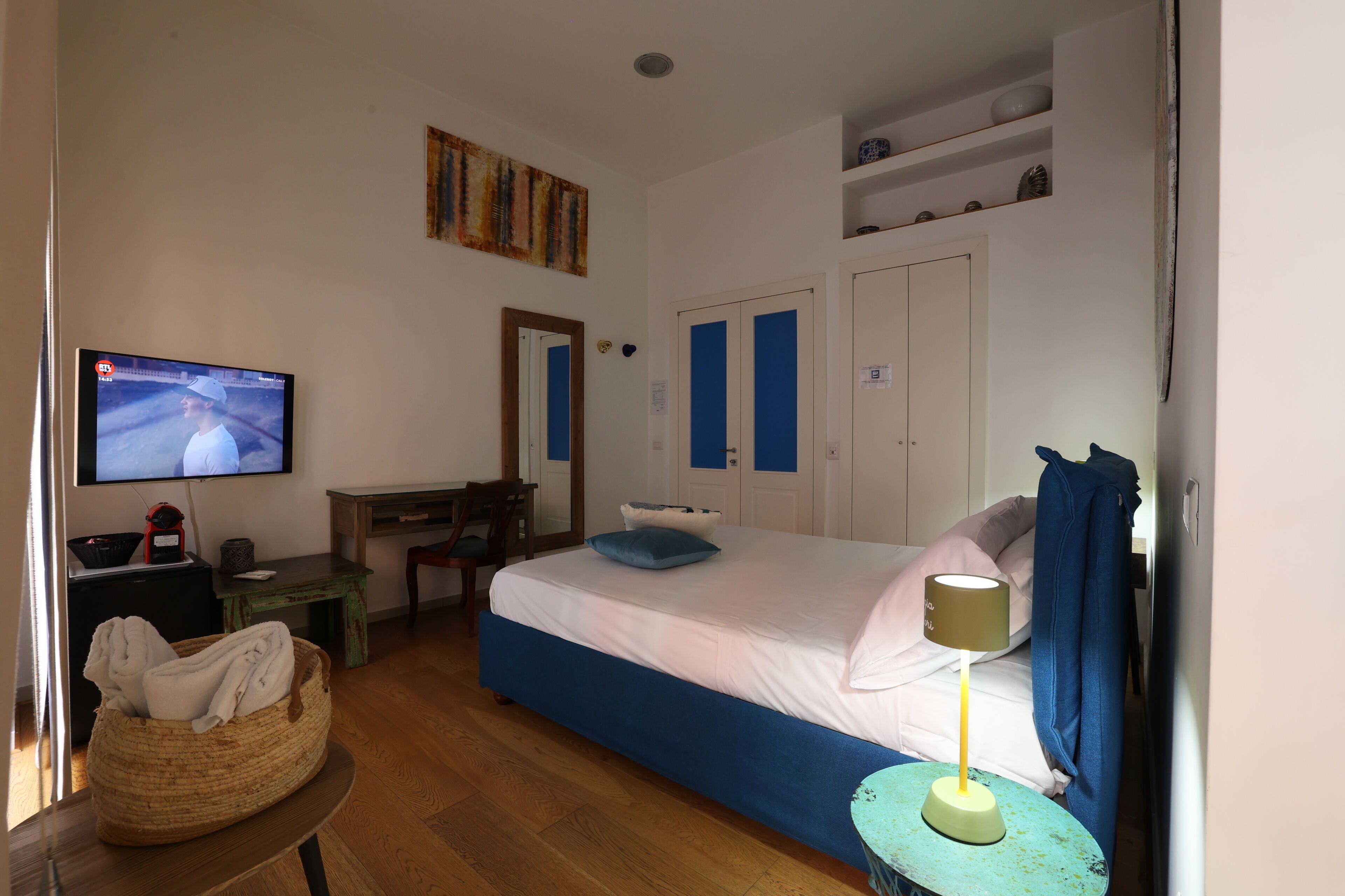Une chambre à coucher comprenant un lit, une télévision, un bureau, une chaise et une petite table avec une lampe.