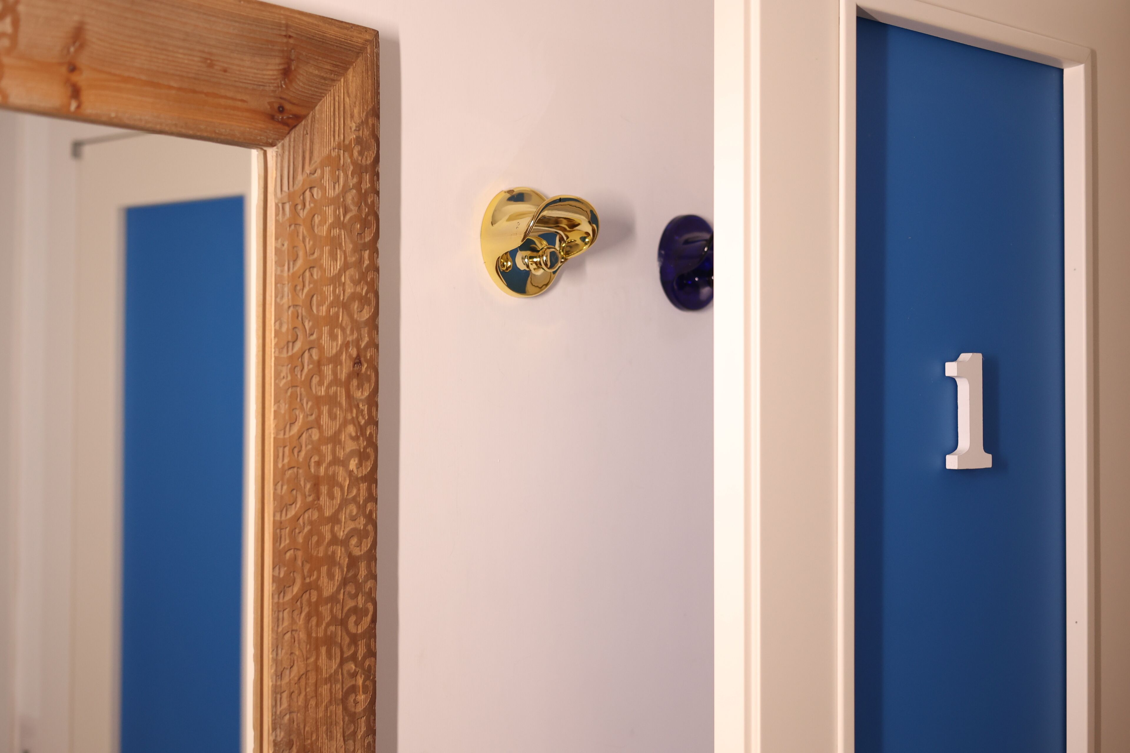 A door with a number '1' sign, a heart-shaped gold door knocker, and a mirror reflecting a blue door.