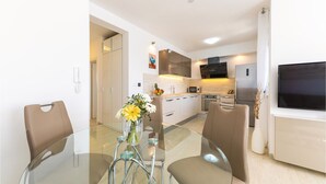 A modern kitchen with a glass dining table, two chairs, and a vase with flowers. - Lovely apartment in Trogir with WiFi (Trogir)