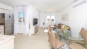 A modern apartment with a kitchen, dining area, and living room. It features a stainless steel refrigerator, a flat-screen TV, a glass dining table with chairs, and a sofa. - Lovely apartment in Trogir with WiFi (Trogir)