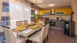 A modern kitchen with yellow cabinets, a dining table with four chairs, and a central island. - Lovely home in Pristeg (Pristeg)