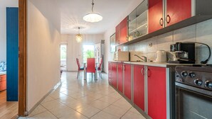 Una cocina moderna con gabinetes rojos, una estufa de acero inoxidable y una cafetera.