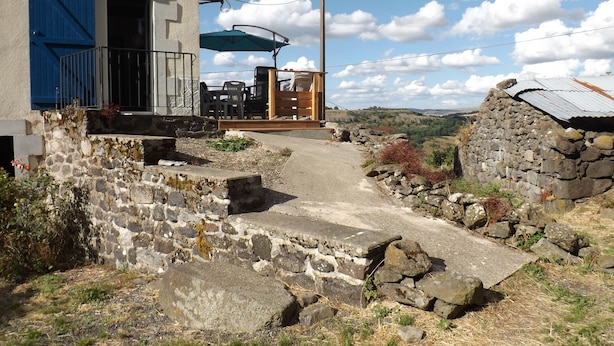 Un edificio rustico in pietra con un balcone e un'area salotto all'aperto.
