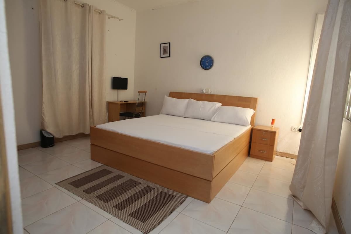 Un dormitorio con una cama grande, una mesita de noche, un armario pequeño y una lámpara.