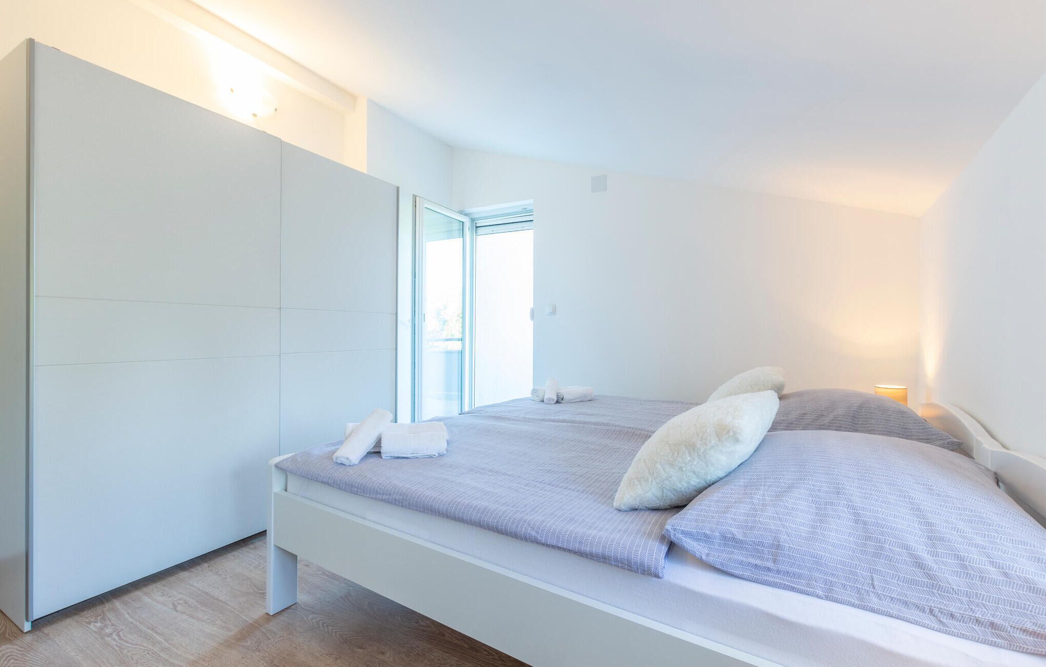 A modern bedroom with a bed, a wardrobe, and a window.
