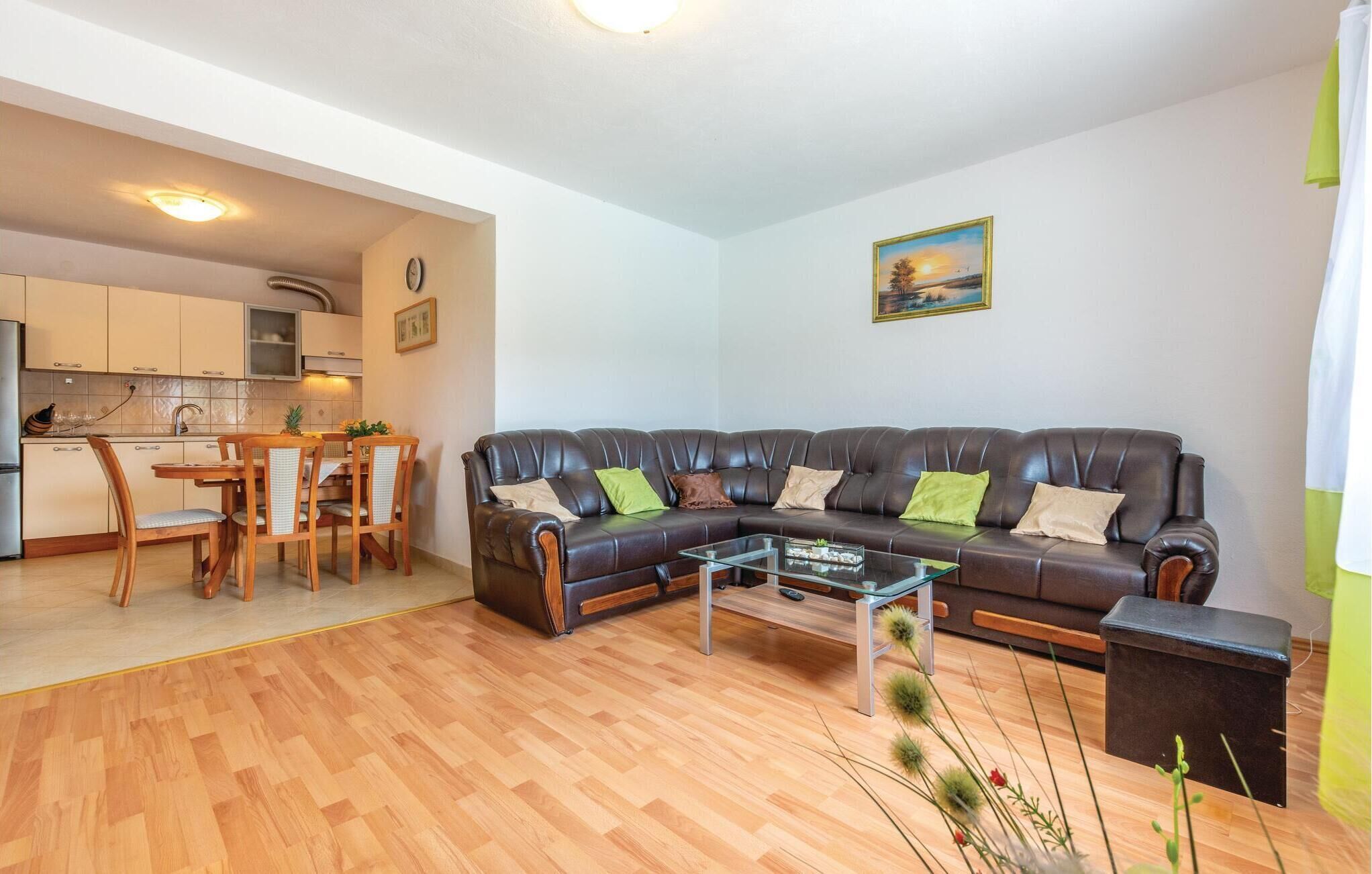 A living room with a leather sofa, a glass coffee table, and a dining area with wooden chairs and a table.