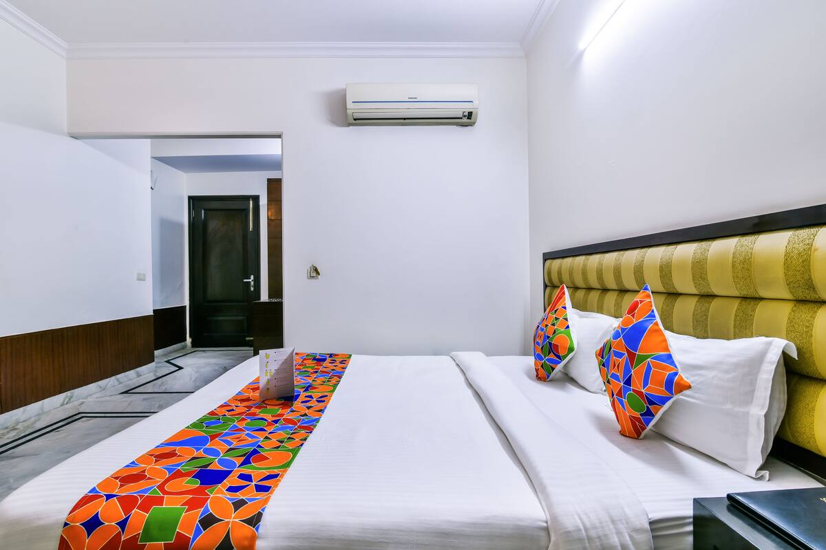 Een hotelkamer met een bed, een bureau, een airconditioner en een kamerbreed tapijt.