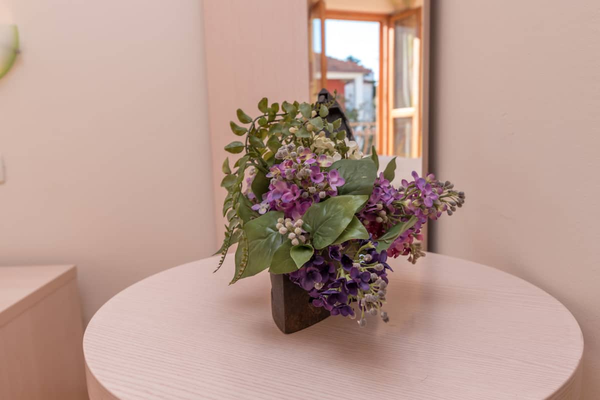 A round table with a floral arrangement in a vase.