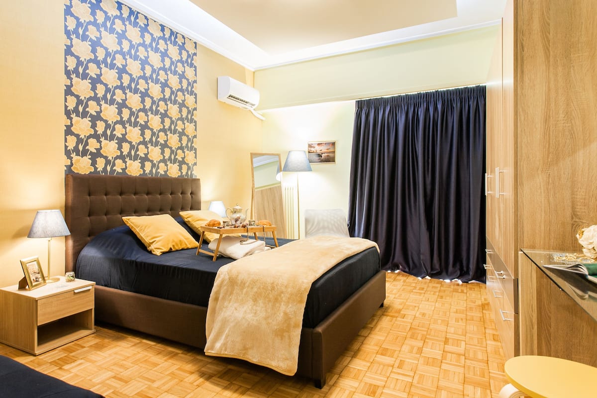 A bedroom with a bed, nightstand, lamp, and a mirror.