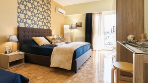 Ein Hotelzimmer mit einem großen Bett, einem Schreibtisch, einem Stuhl, einer Lampe und einem fenster mit Vorhängen.