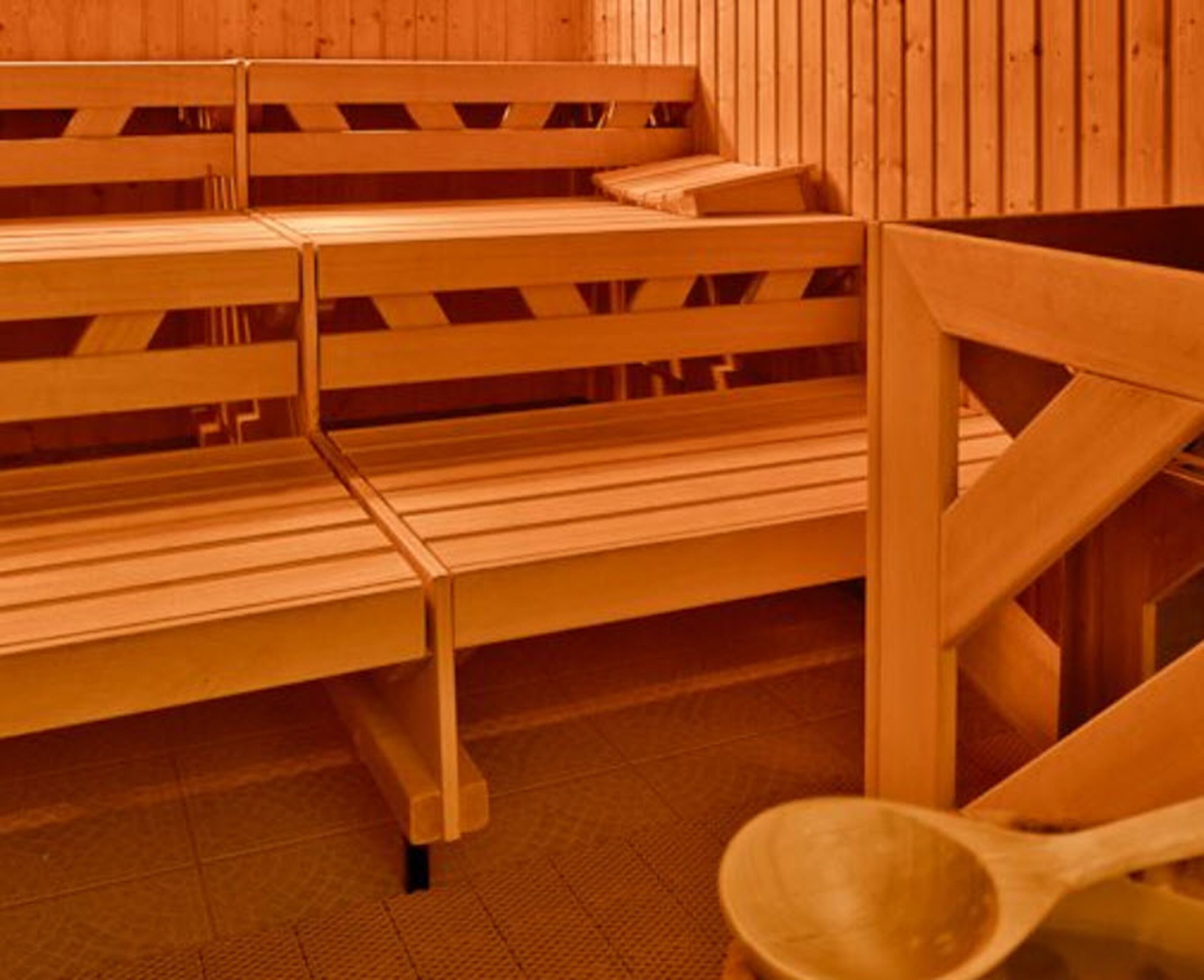 Uma sauna com bancos de madeira e uma tigela de madeira.