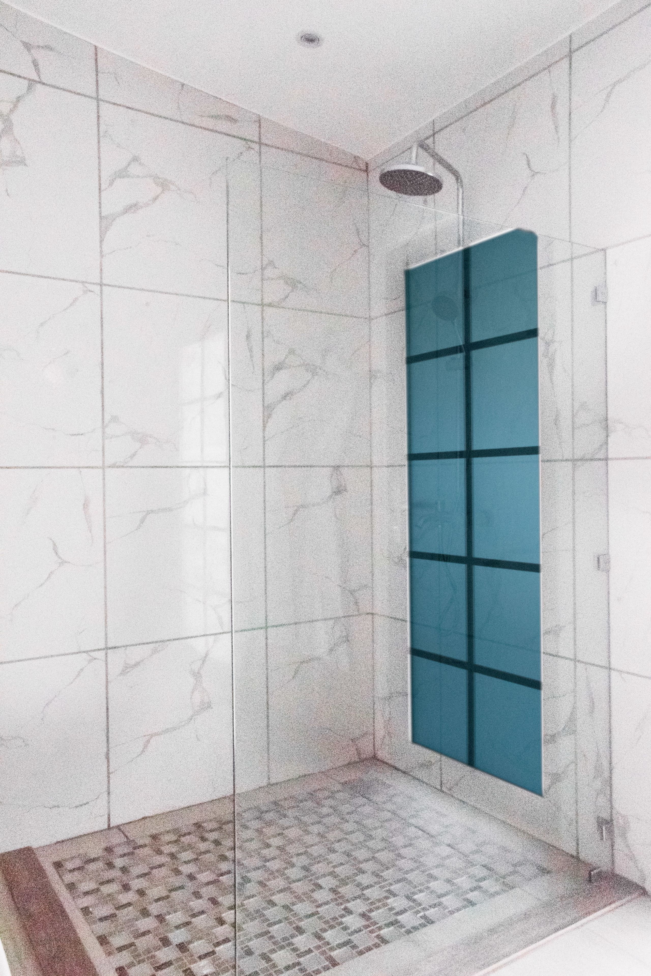 A modern bathroom with white marble tiles, a glass shower enclosure, and a patterned floor.