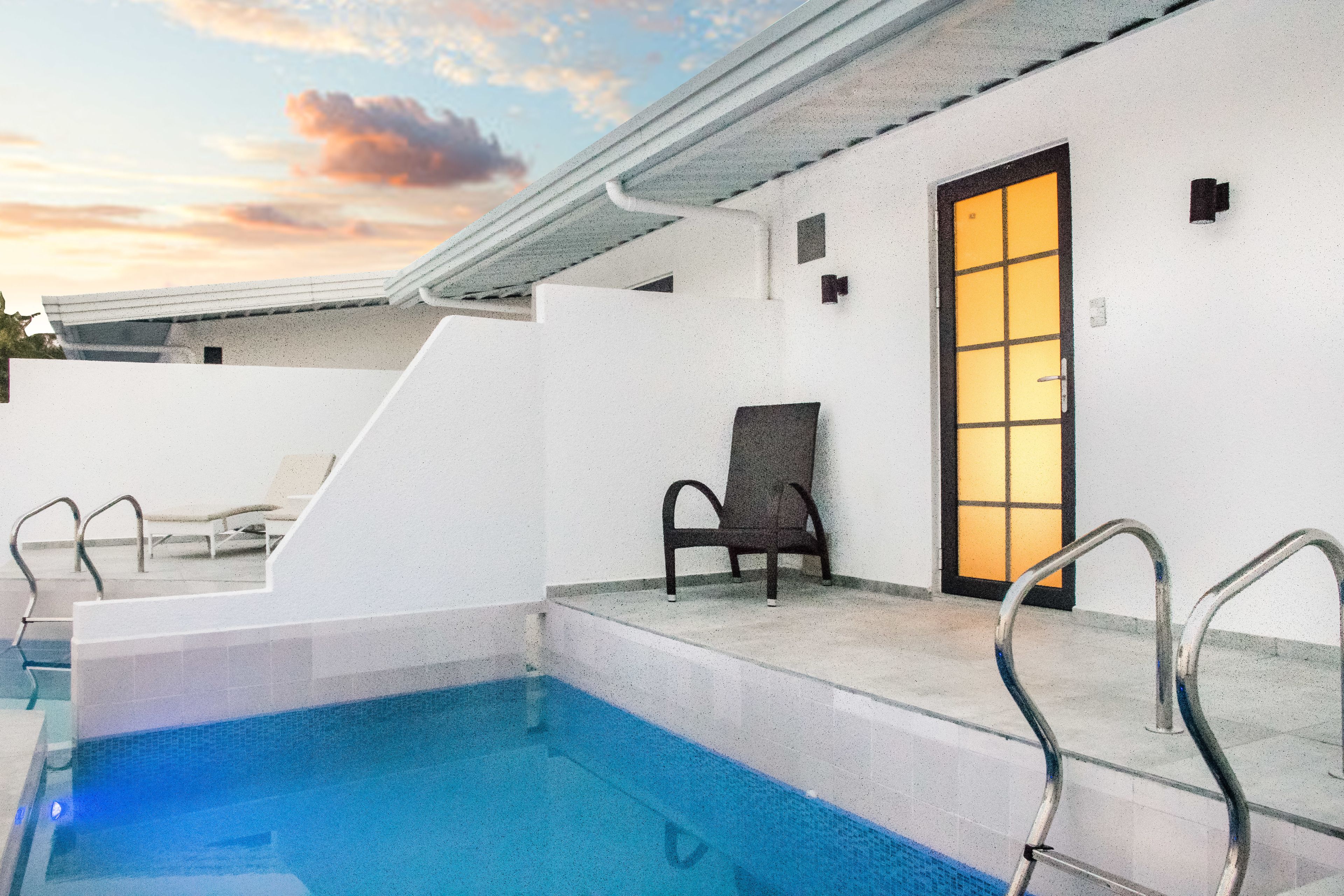 A swimming pool area with a chair and a door.