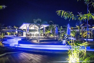 Una piscina al aire libre, sombrillas, sillones reclinables de piscina