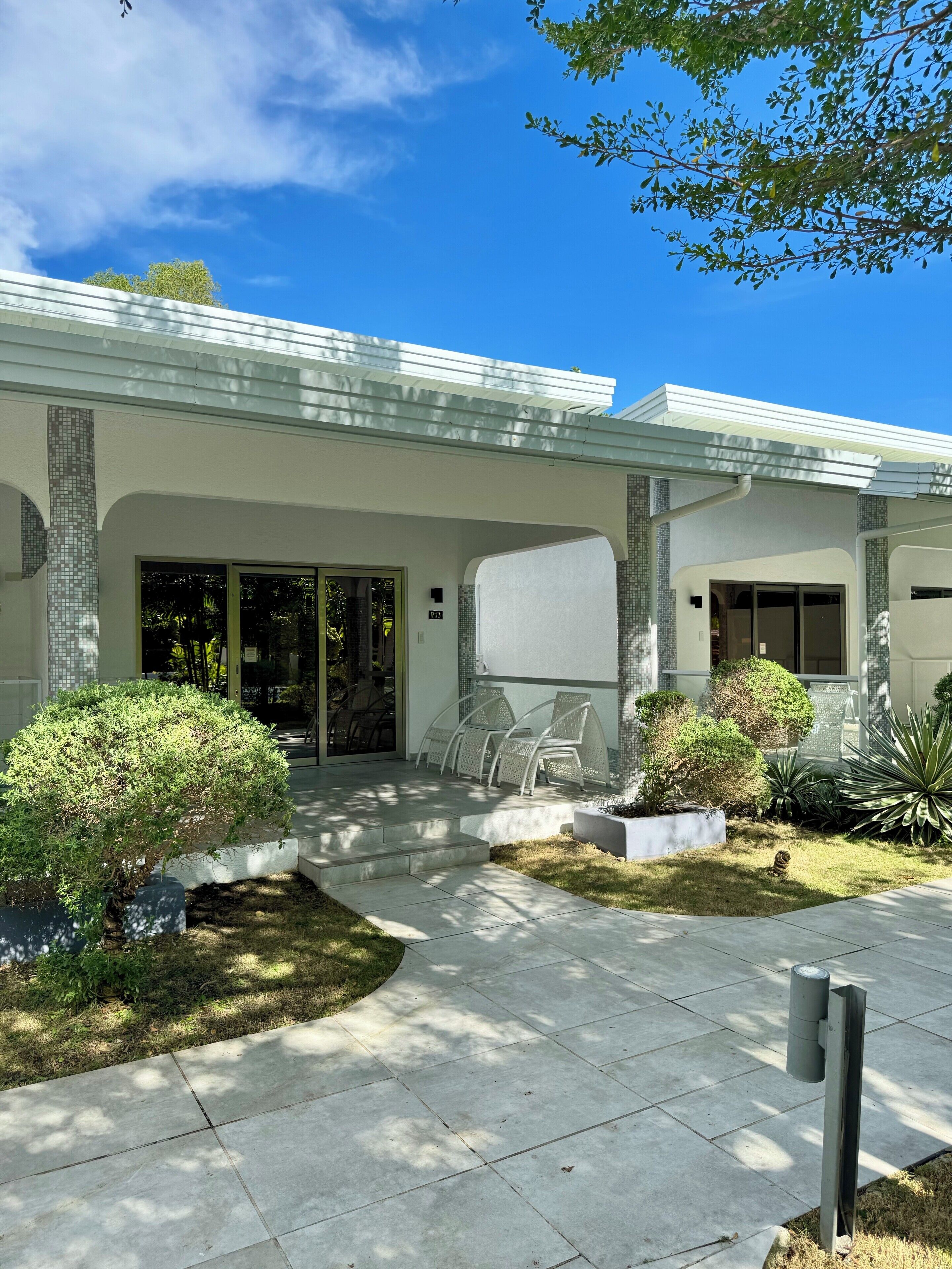 A modern house with a covered patio, outdoor seating, and well-maintained landscaping.