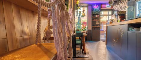Una zona de bar con mostrador de madera, adornos de cuerda y un área de estar con vista al bar.