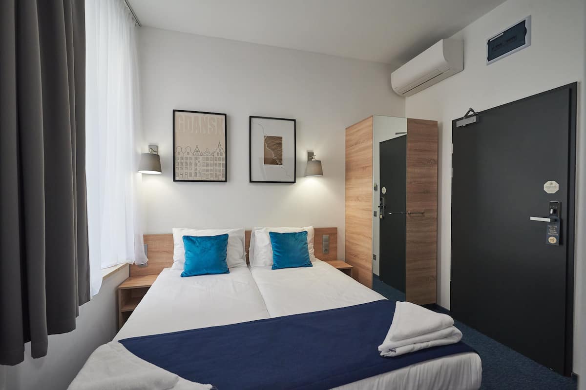 Una habitación de hotel con una cama grande, dos mesitas de noche, un armario y una puerta.