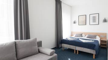 A hotel room with a bed, a sofa, and a nightstand.