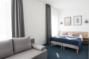 A hotel room with a bed, a sofa, and a nightstand.