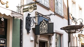 Um edifício com a placa 'Fama Residence' e um caixa eletrônico 'Bankomat'.