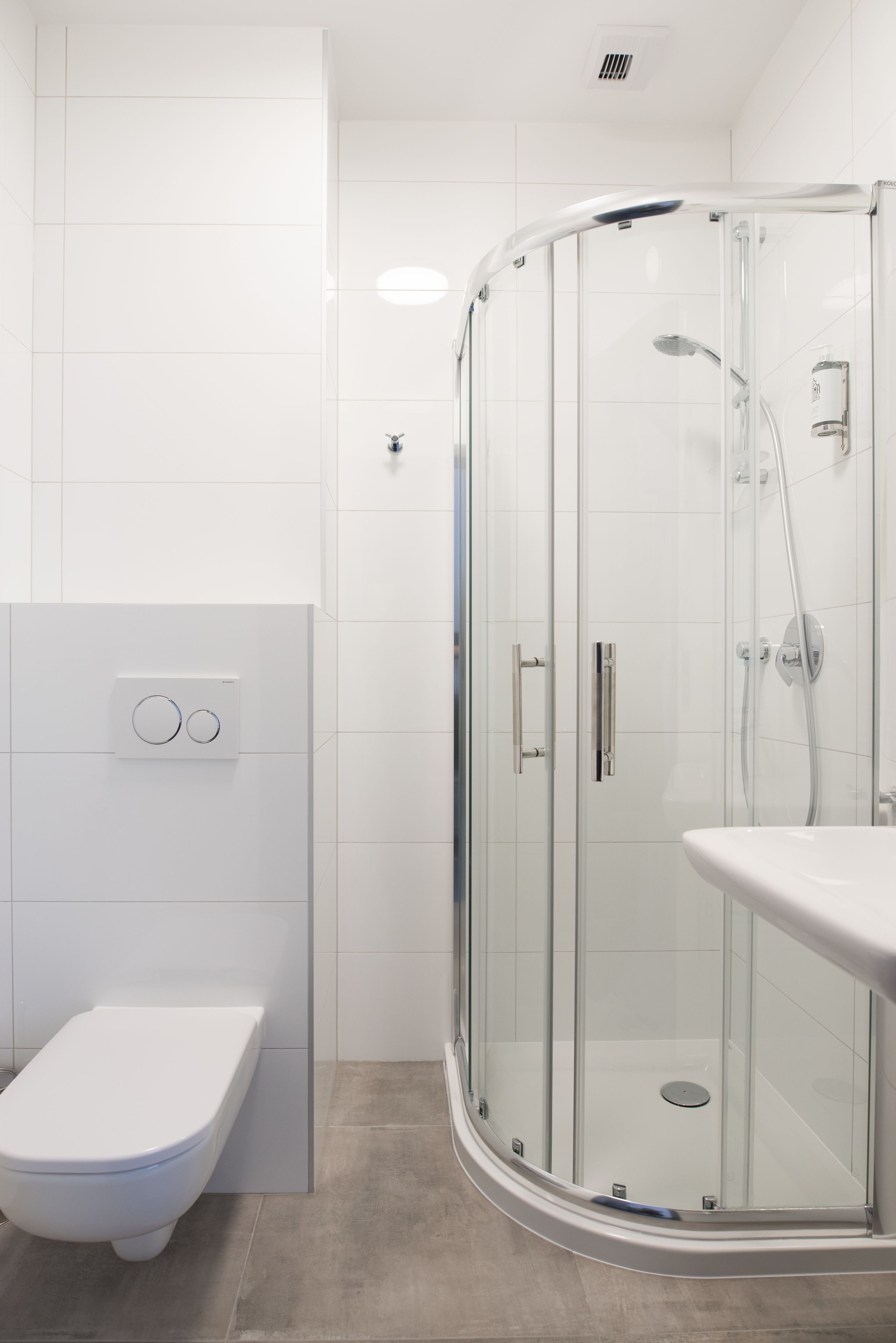 Une salle de bain moderne dotée d’une douche à parois de verre, de toilettes et d’un lavabo.