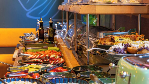 Um buffet com diversos alimentos e utensílios.