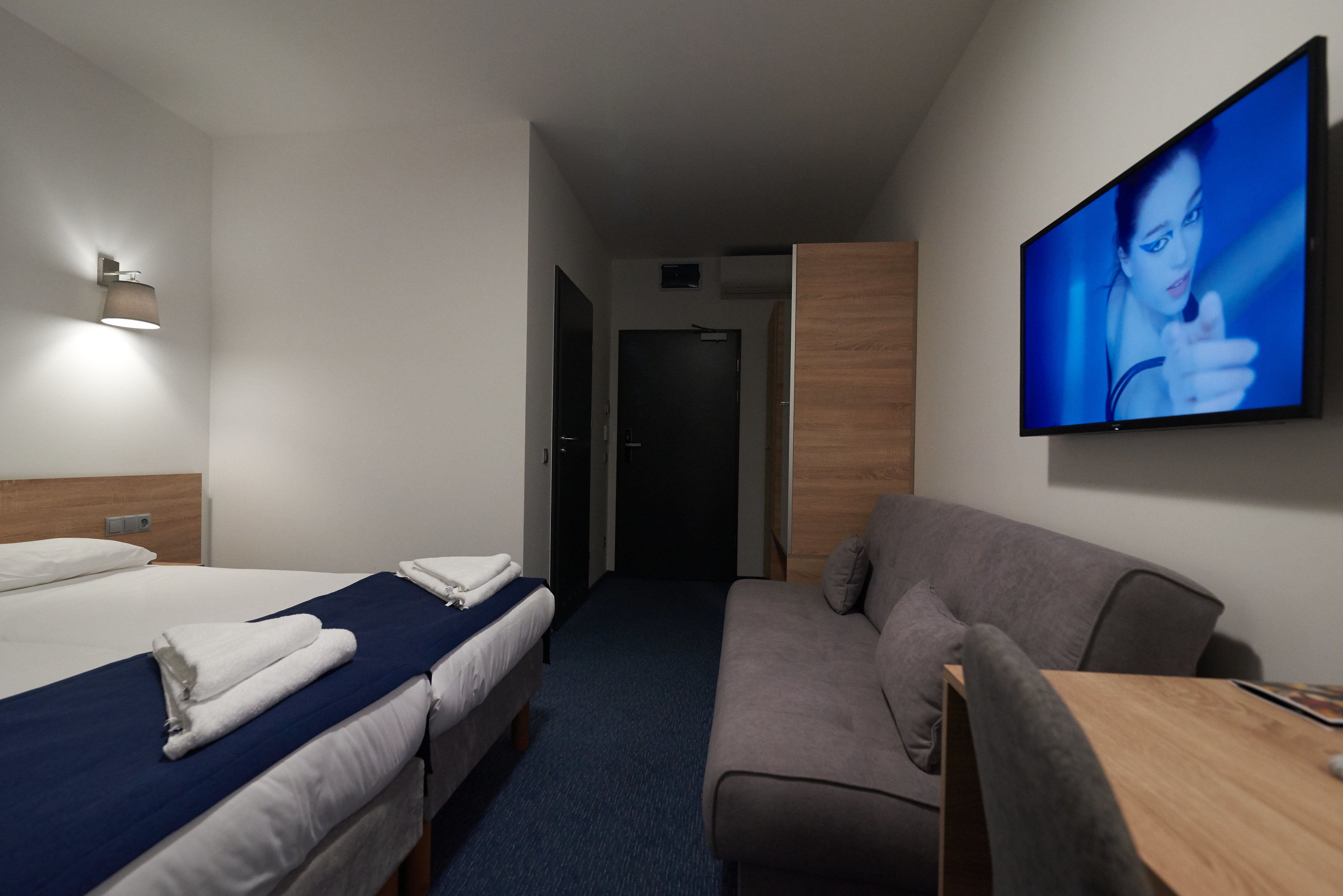 Habitación de hotel con dos camas, un sofá, un televisor y un armario de madera.
