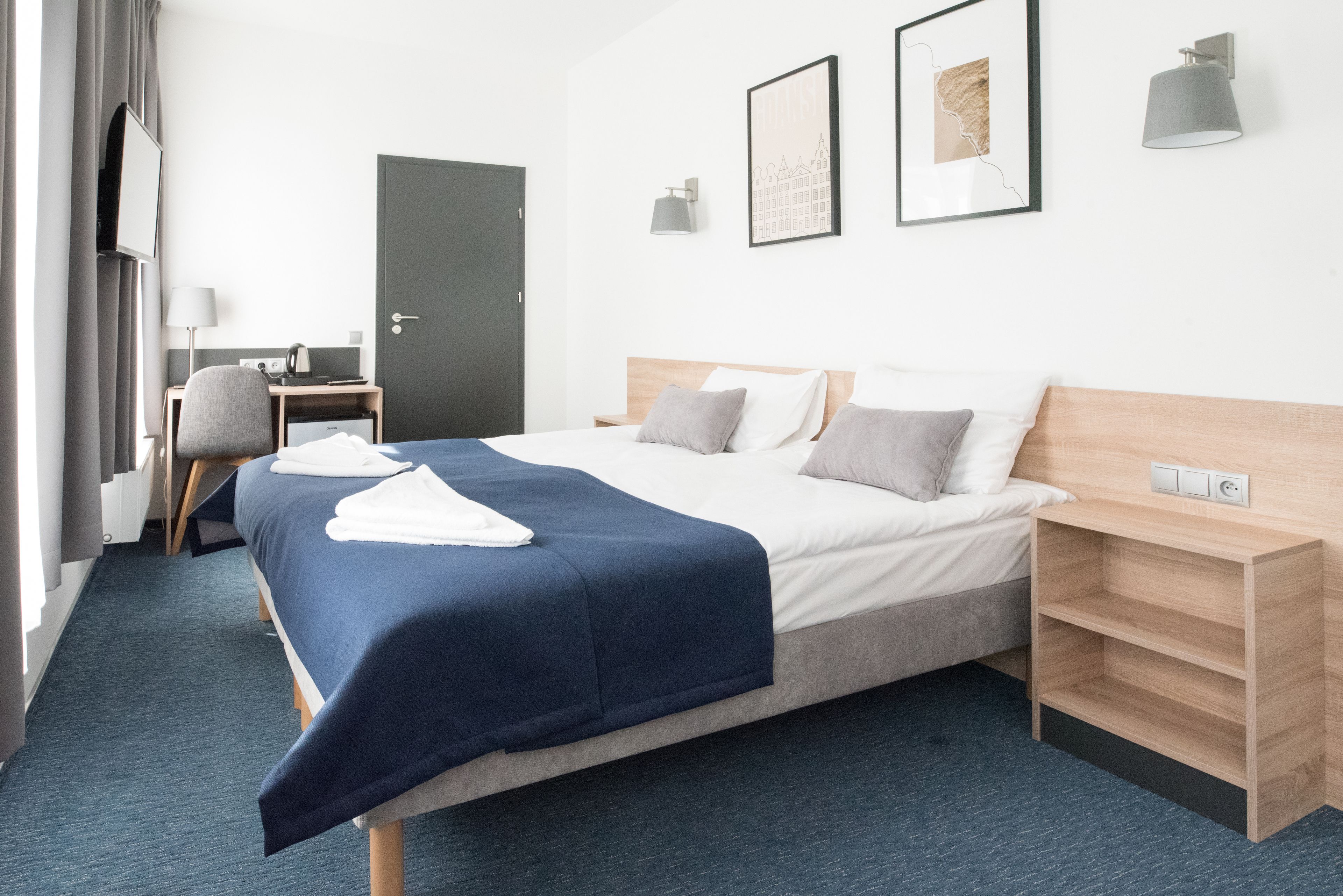 A hotel room with a bed, a desk, a chair, and a wardrobe.