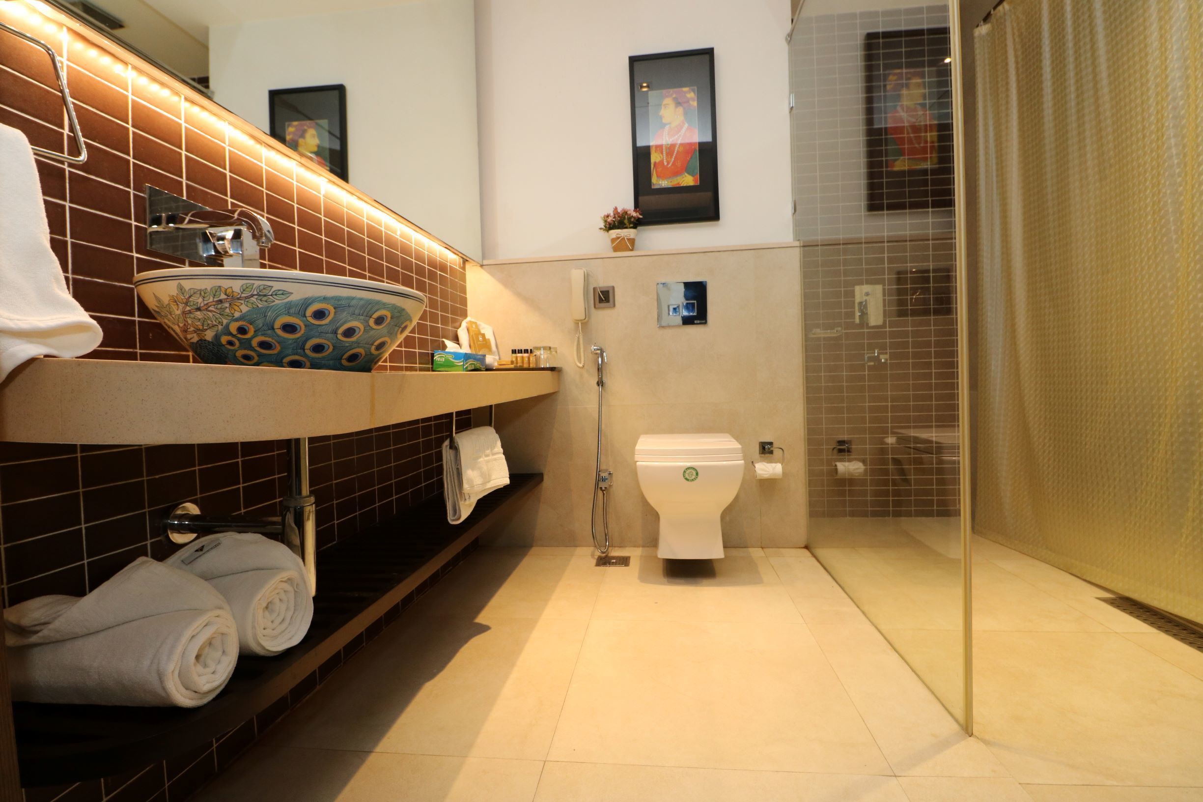 A modern bathroom with a tiled backsplash, a decorative bowl sink, a toilet, and a glass shower enclosure.