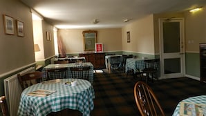 A dining area with checkered tablecloths, wooden chairs, a mirror, and a door. - The Castle Hotel (Coldstream)