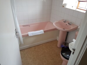 Un baño con una bañera rosa, un lavabo y un inodoro.