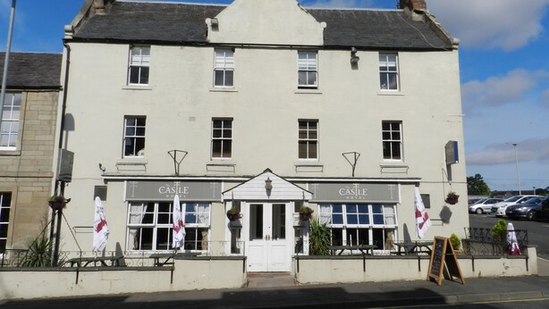 A two-story building with a sign reading "The Castle Hotel" at the entrance. - The Castle Hotel (Coldstream)