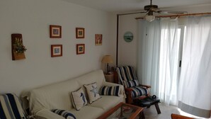 A living room with a sofa, armchairs, a coffee table, and a ceiling fan. - Bitacora 4º Solo Familias! (Xeraco Playa)