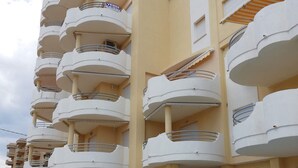 A multi-story hotel with balconies, a swimming pool, and a clear sky. - Bitacora 4º Solo Familias! (Xeraco Playa)