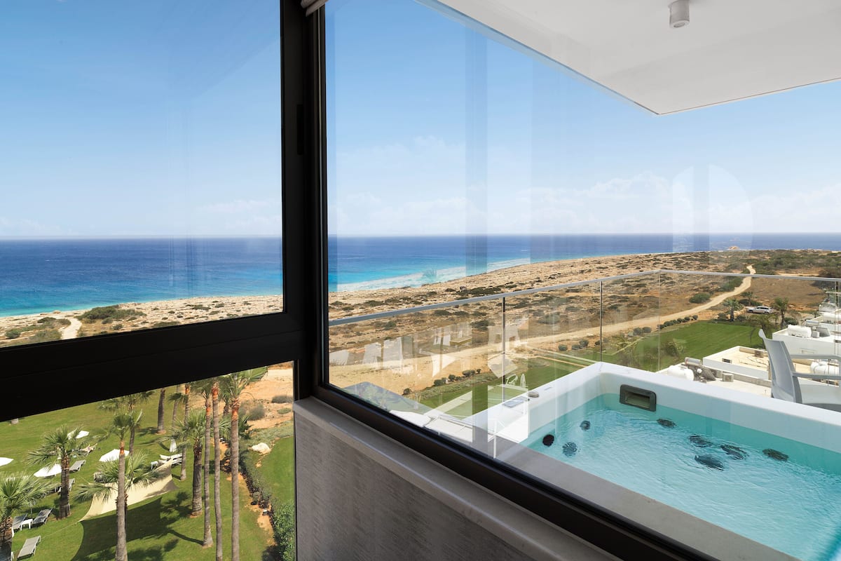 Vista desde un balcón con piscina, que da a una playa y un campo de golf.
