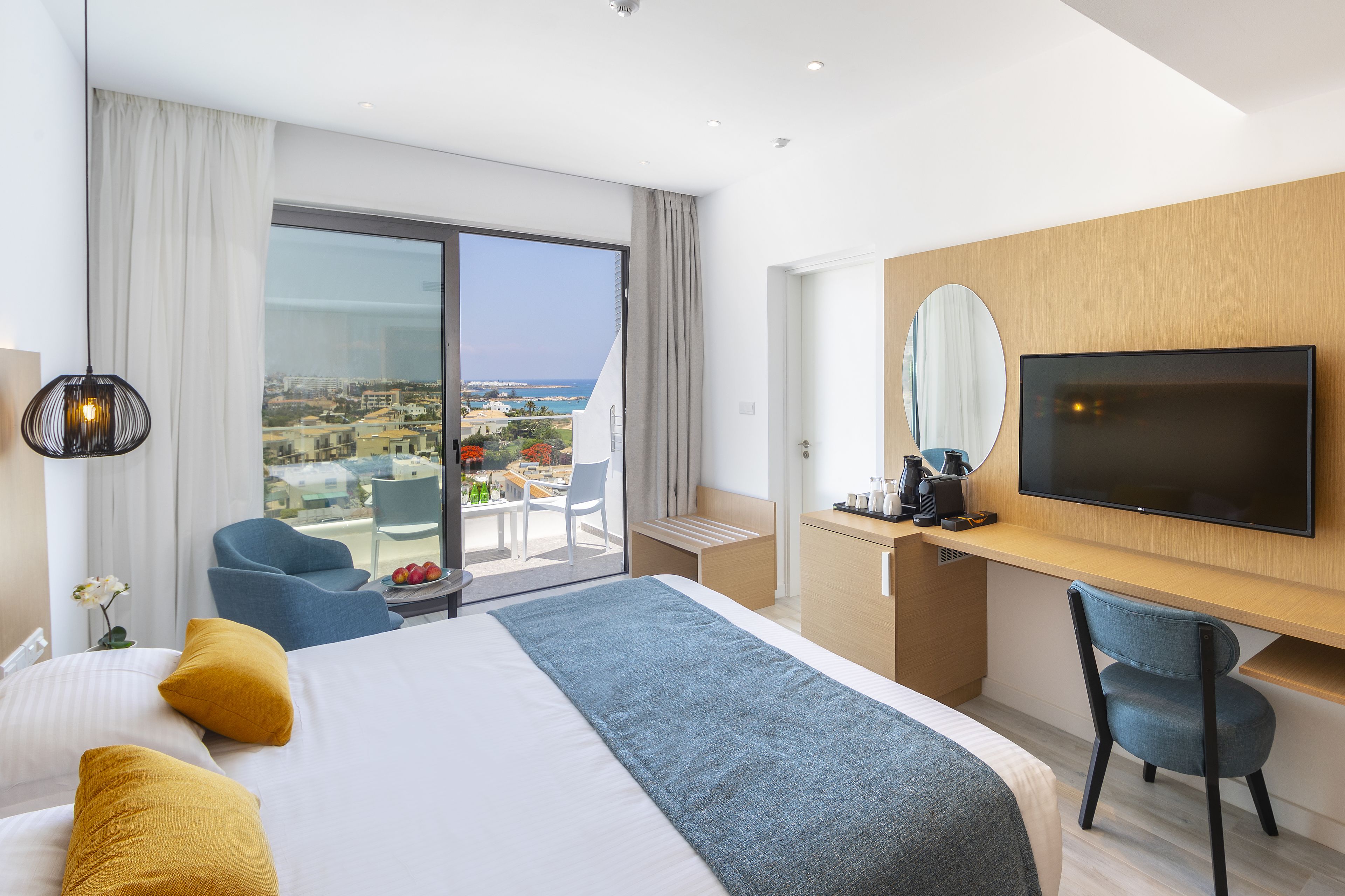 Ein Hotelzimmer mit Bett, Schreibtisch, Fernseher und Blick auf die Stadt.