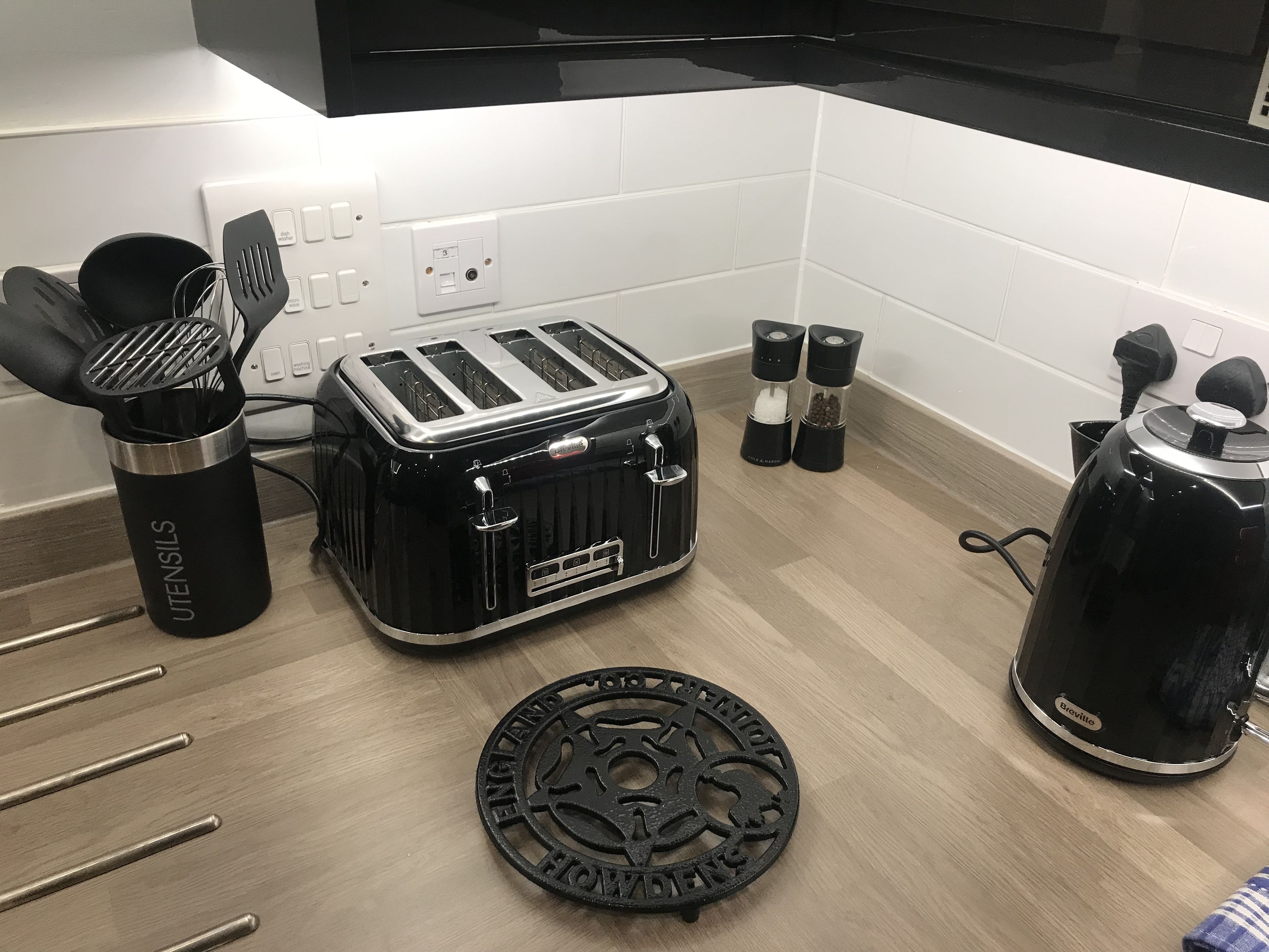 A kitchen with a toaster, a kettle, salt and pepper shakers, and a utensil holder.