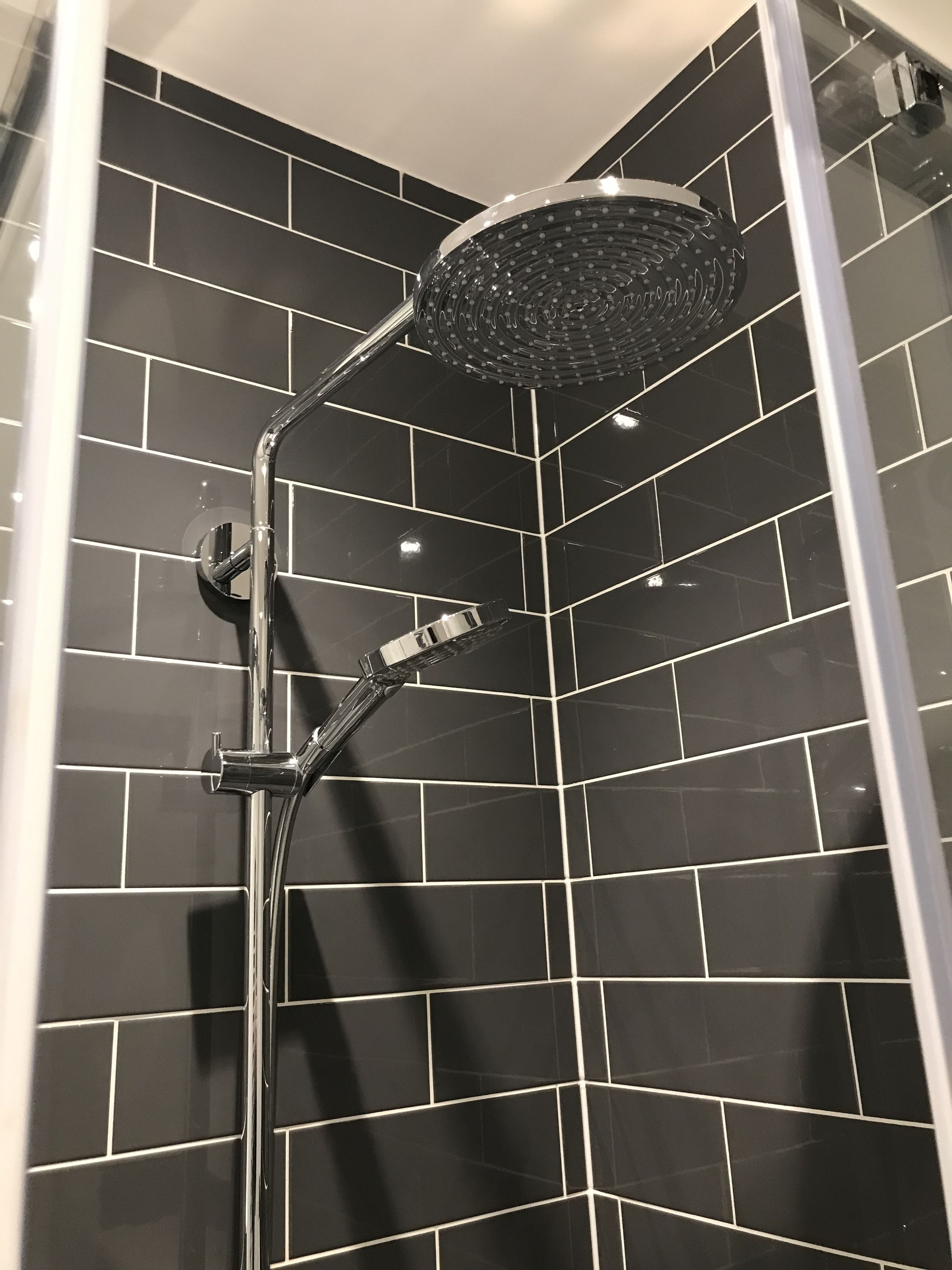 A shower with a modern design, featuring a curved showerhead and chrome fixtures.