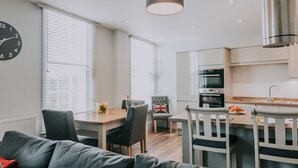 Et moderne køkken med spiseområde, sofa og et flag på en stol.