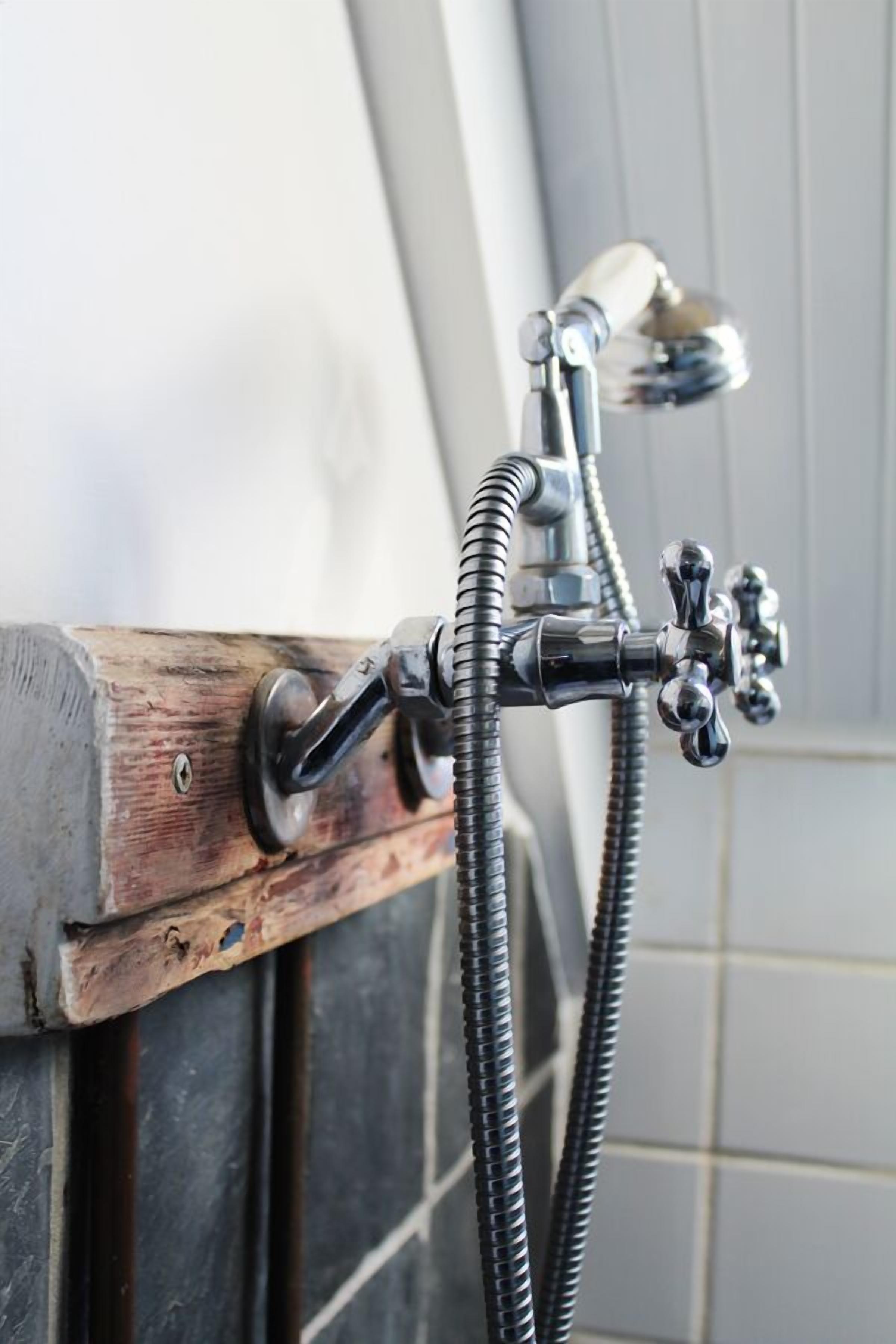 A bathroom with a shower head mounted on a wooden frame.