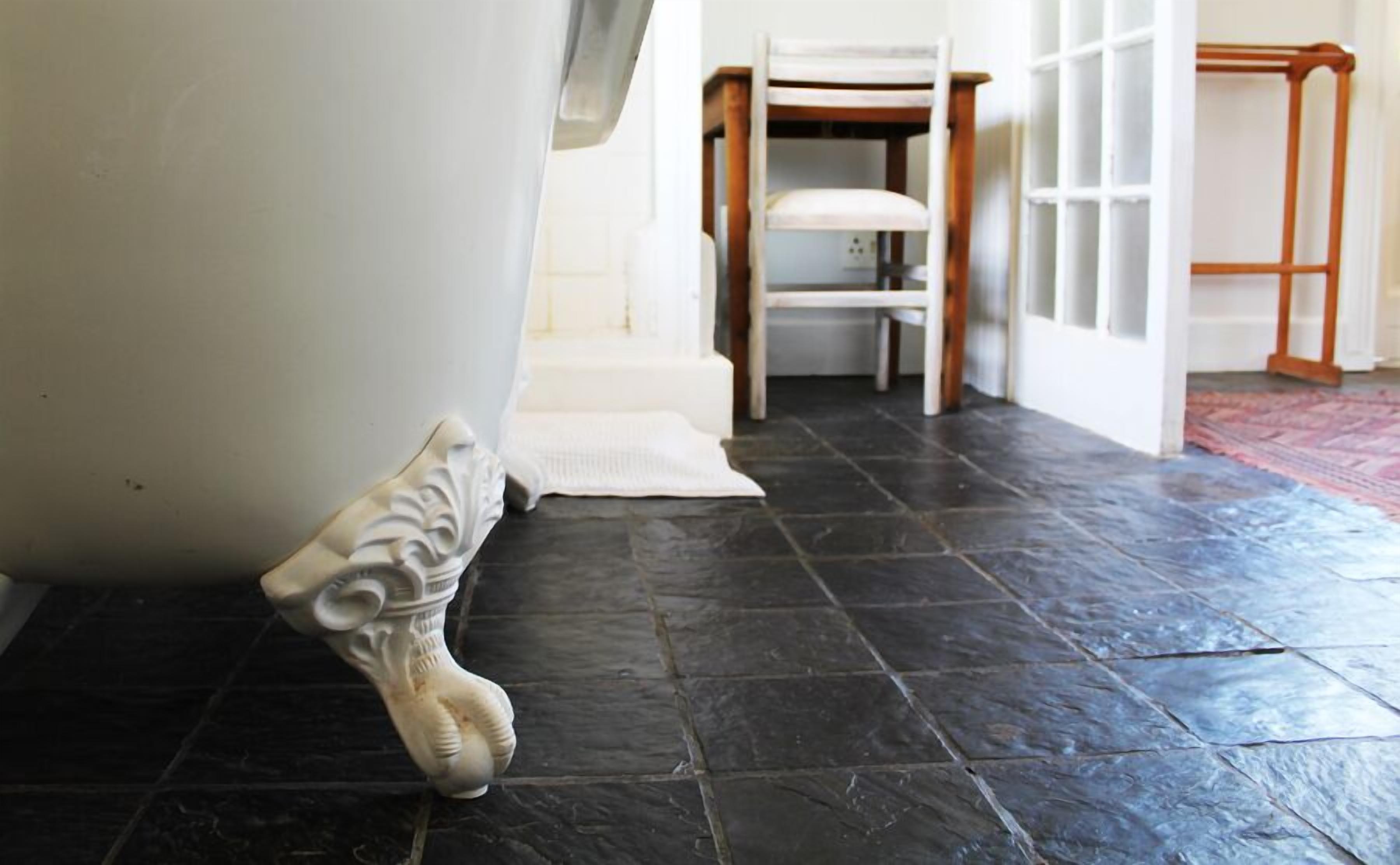 Une salle de bain avec une baignoire, une chaise blanche et une chaise en bois.