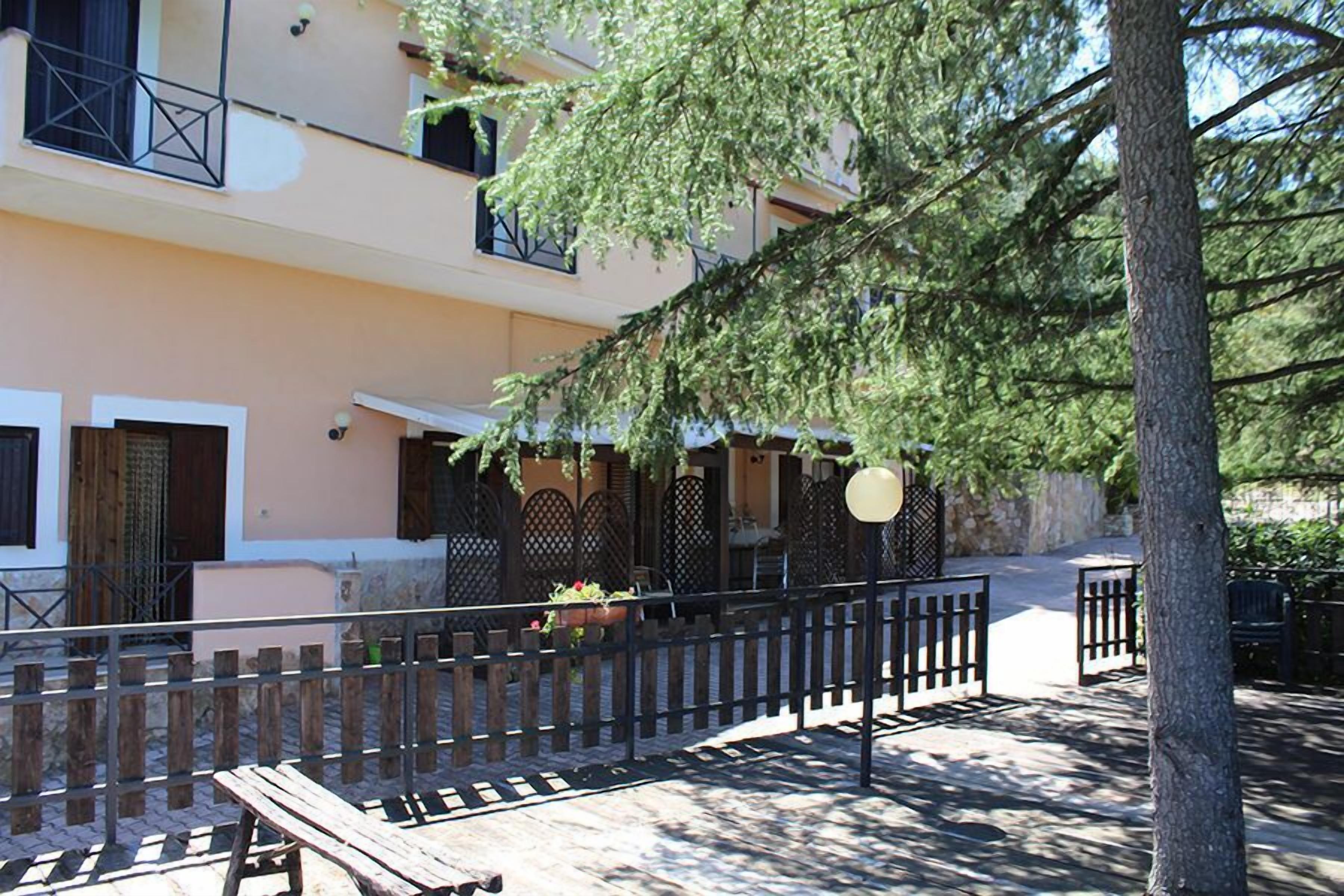 Un patio con un banco de madera, una cerca de metal y un edificio con balcones y ventanas.